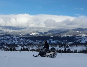Snowmobiler on the trail overlooking the mountains.