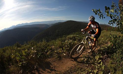 A solo bike races by a steep ridge while mountain biking in Colorado.